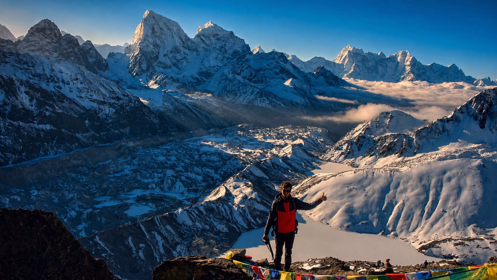 Trekker at Gokyo Ri overlooking Everest Three High Passes snow covered peaks and Gokyo Lakes