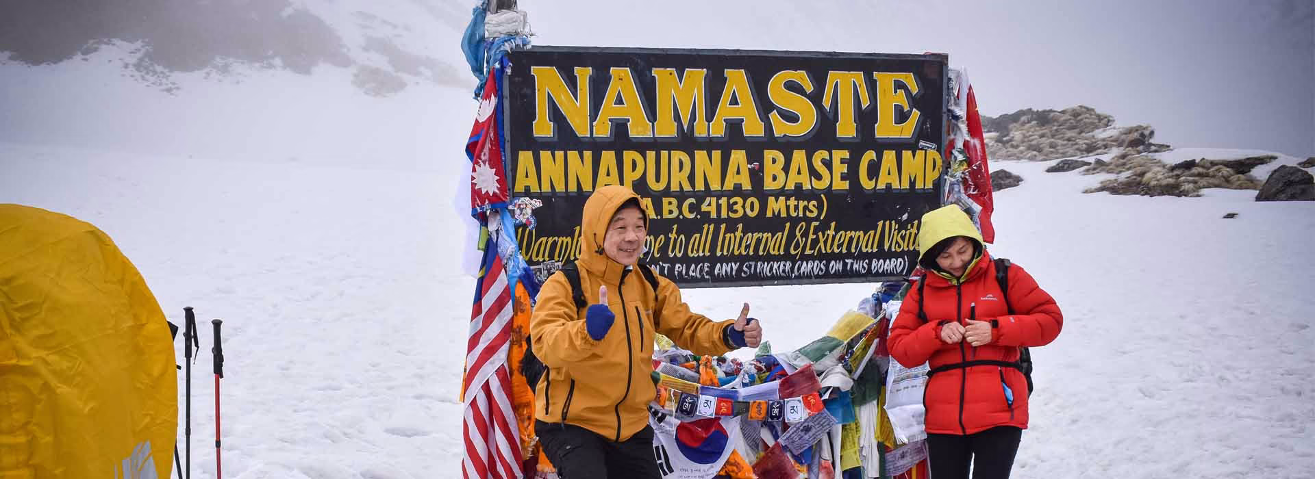 Two trekkers posing at Annapurna Base Camp summit point in Nepal