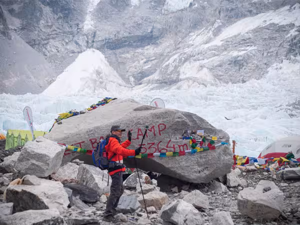 Trekker at the Everest Base Camp elevation marker at 5,364 metres