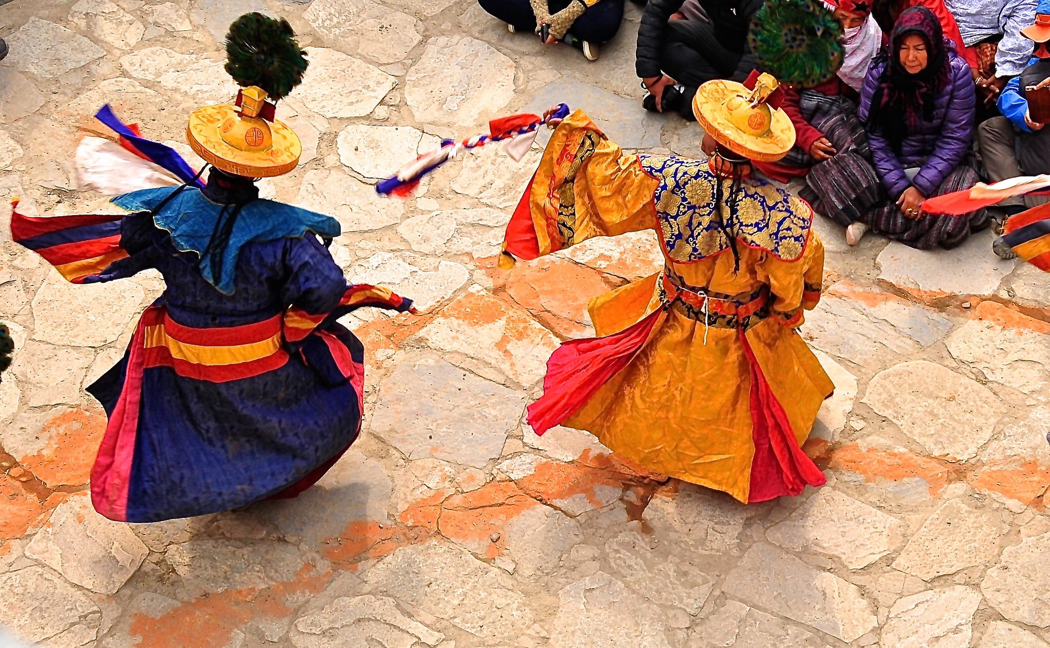 Two dancers with bright costumes perform a ritual dance.