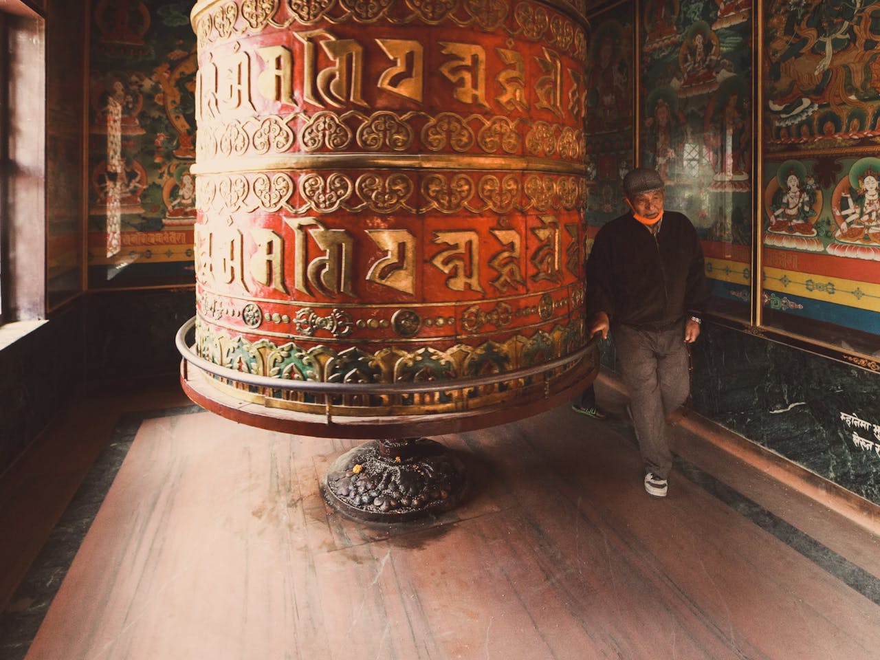 Man circumambulating a prayer wheel in Nepal, clockwise circumambulation is the norm.