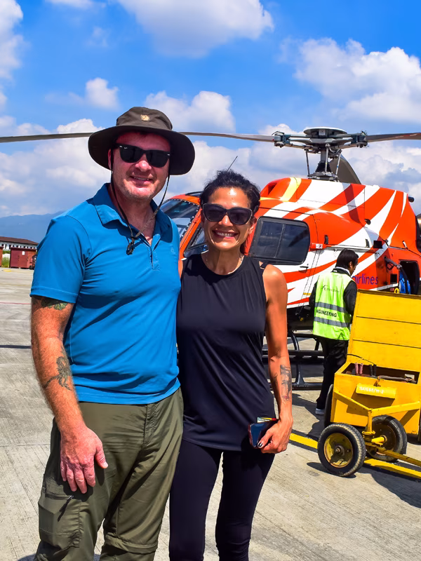 Couple posing in front of a helicopter before the Everest Base Camp Helicopter Tour in Lukla.
