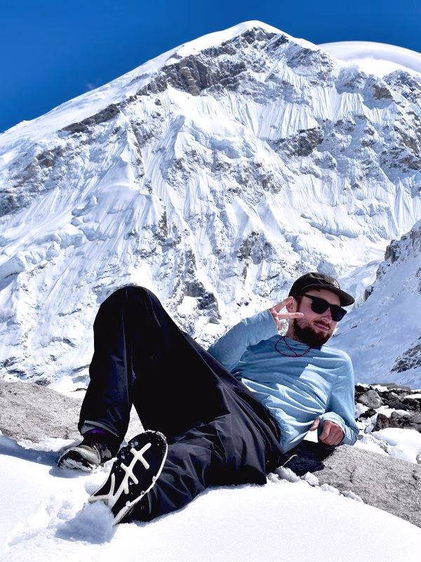 Trekker posing on a snowy ridge with Mount Everest in behind during the luxury Everest Base Camp Trek in Nepal