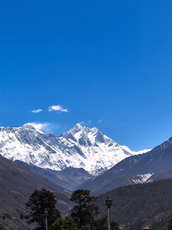 Panoramic Himalayan view from Tengboche during the Everest View Trek with lush greenery and blue skies.